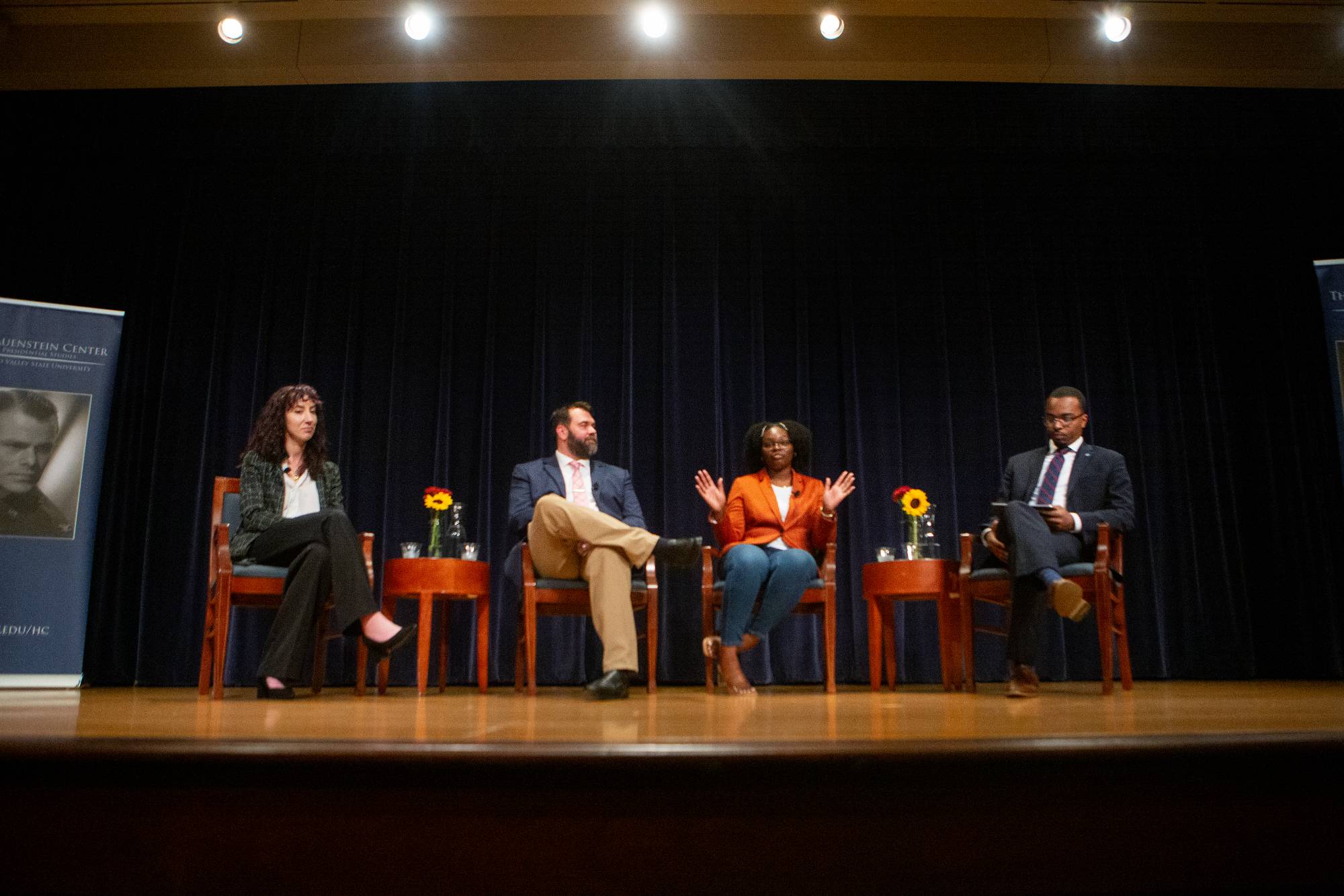 four people sitting in chairs on a stage